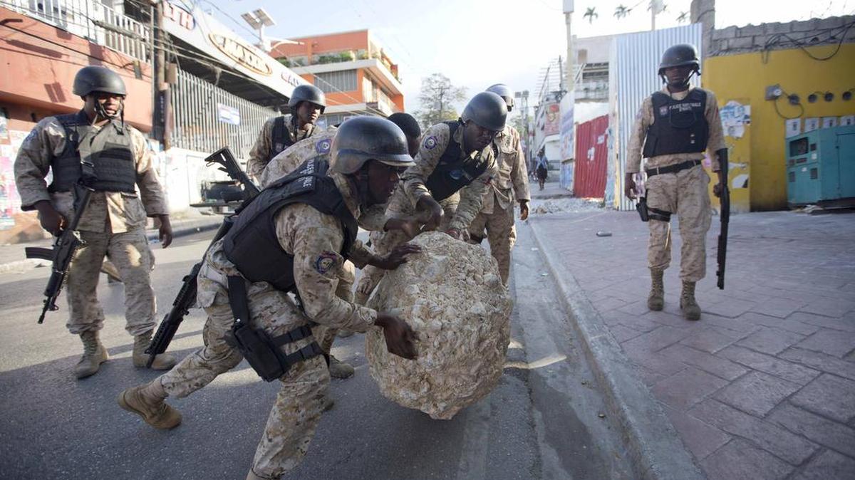 National police officers remove a rock used as a street barricade by demonstrators after a protest against the results of Oct. 25 elections, in Port-au-Prince, Haiti, Wednesday, Nov. 18, 2015. The demonstrators are claiming fraud in the recent first round of elections. The demonstrators are organized by three political parties who have joined to demand the cancellation of the Oct. 25 presidential election, or removal of ruling party candidate Jovenel Moise who is set to face Jude Celestin in a Dec. 27 presidential runoff election.
