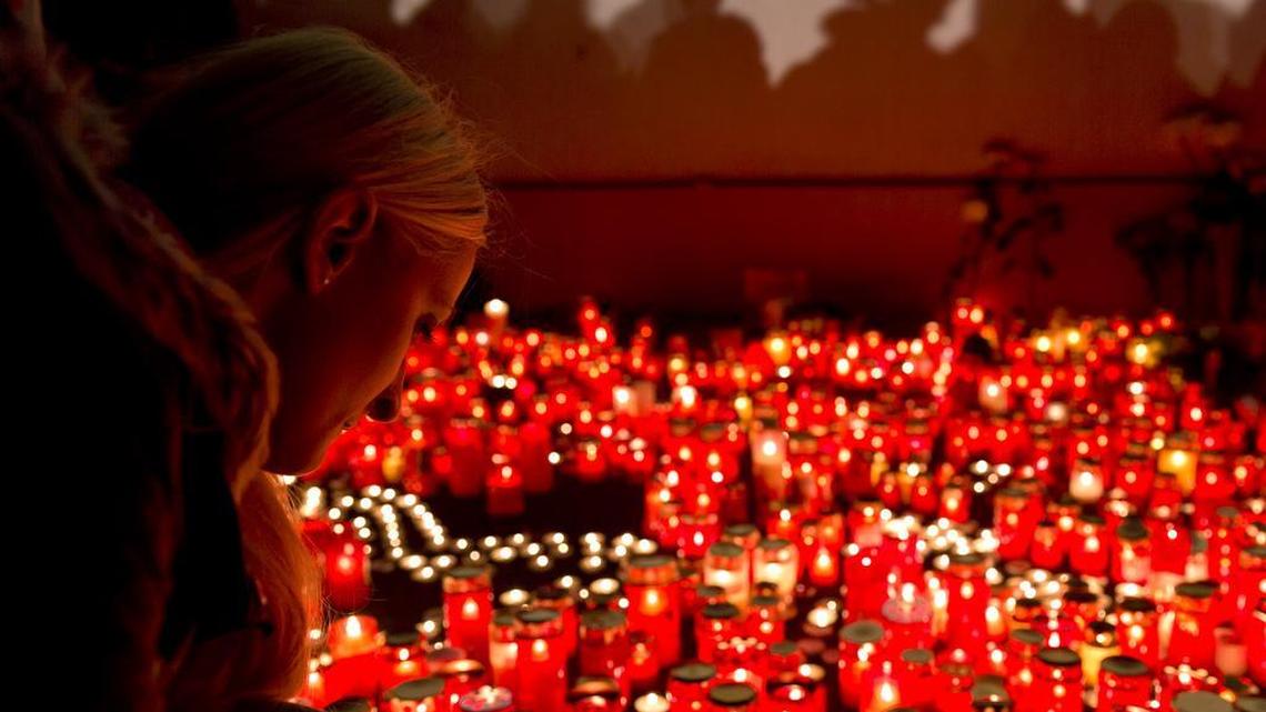 A girl lights candles outside the compound that housed the hip Colectiv nightclub where a fire occurred in the early morning hours in Bucharest, Romania, Oct. 31, 2015.