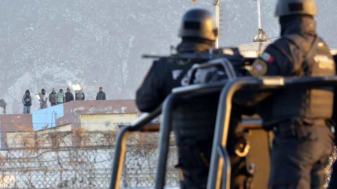 Inmates stand on the rooftop of the Topo Chico prison as police stand guard on the perimeters, after a riot broke out around midnight, in Monterrey, Mexico, Thursday, Feb. 11, 2016. Dozens of inmates were killed and several injured in a brutal fight between two rival factions at the prison in northern Mexico, the state governor said.