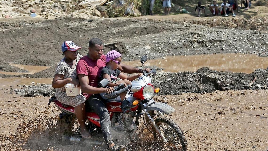 A family rides through the La Digue river, four days after Hurricane Matthew barreled through the southwestern tip of the country.