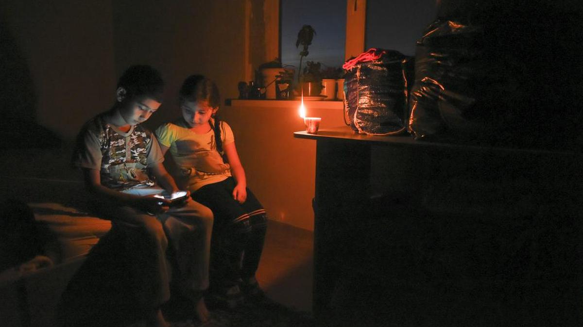 Ethnic Crimean tartar children play on a cell phone in candlelight at their home after a power failure in a village outside Simferopol, Crimea, on Sunday. Russia's Energy Ministry says nearly 2 million people on the Crimean Peninsula are without electricity after two transmission towers in Ukraine were damaged by explosions.