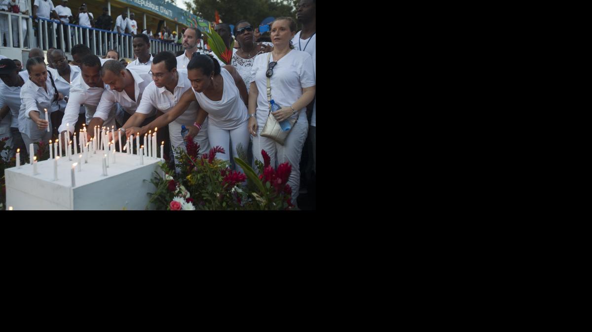 
Families and friends light candles on a memorial during a vigil at the site of an accident that left at least 16 people dead in Port-au-Prince, Haiti, Tuesday. Officials say a man on top of a musical group’s float was shocked by high-voltage wires above the street, setting off a panic in which dozens of people were trampled.
