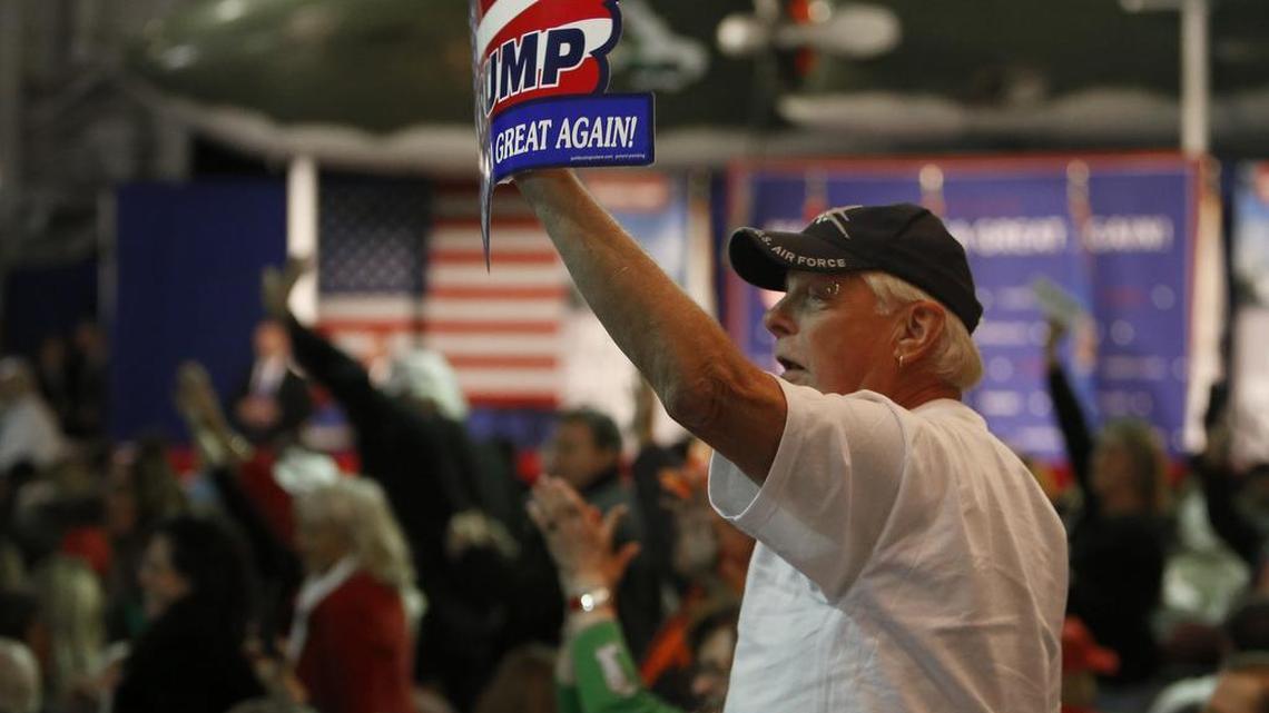 Supporters for Donald Trump wave to the press after being prodded by Republican presidential candidate, businessman Donald Trump, during a rally coinciding with Pearl Harbor Day at Patriots Point aboard the aircraft carrier USS Yorktown in Mt. Pleasant, S.C., Monday, Dec. 7, 2015.