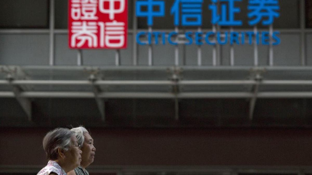 In this Wednesday, Aug. 26, 2015 file photo, elderly Chinese women walk near the logo for Citic Securities in Beijing. Shares in Citic Securities Ltd. and Guosen Securities Ltd., both declined by the 10 percent daily limit in trading in China Friday, Nov. 27, 2015, after both said that they were under investigation for possible violation of securities market rules.