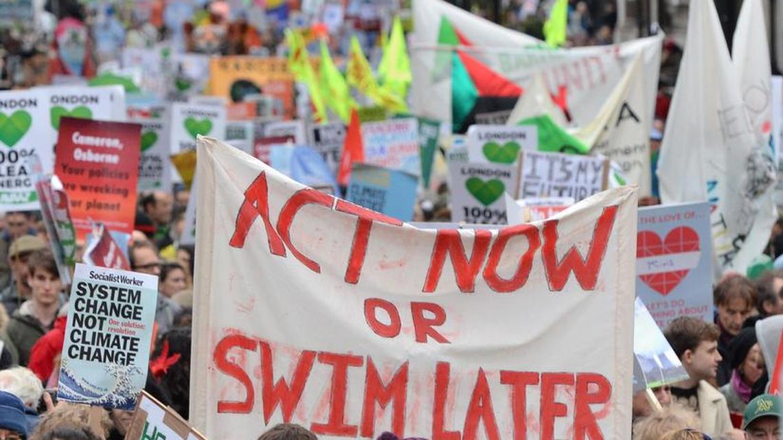 Campaigners hold a banner calling for everybody to act now or swim later, as demonstrators move through the streets of central London, campaigning for ambitious action to tackle climate change on Sunday Nov. 29, 2015. Campaigners want the Government and other countries to agree on a deal that will shift the world to renewable energy and protect people from the impacts of climate change.