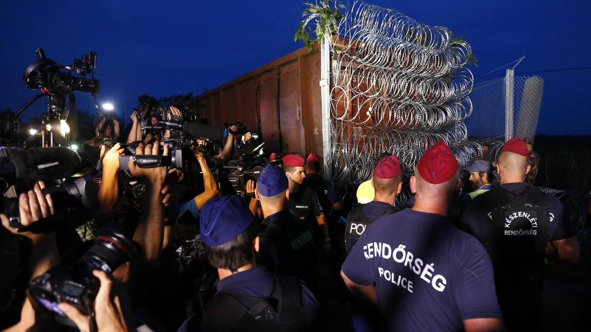 
Hungarian police officers guard the area as a rail wagon prepared with razor wire arrives to seal the border fence between Serbia and Hungary in Roszke, southern Hungary, Monday, Sept. 14, 2015. 
