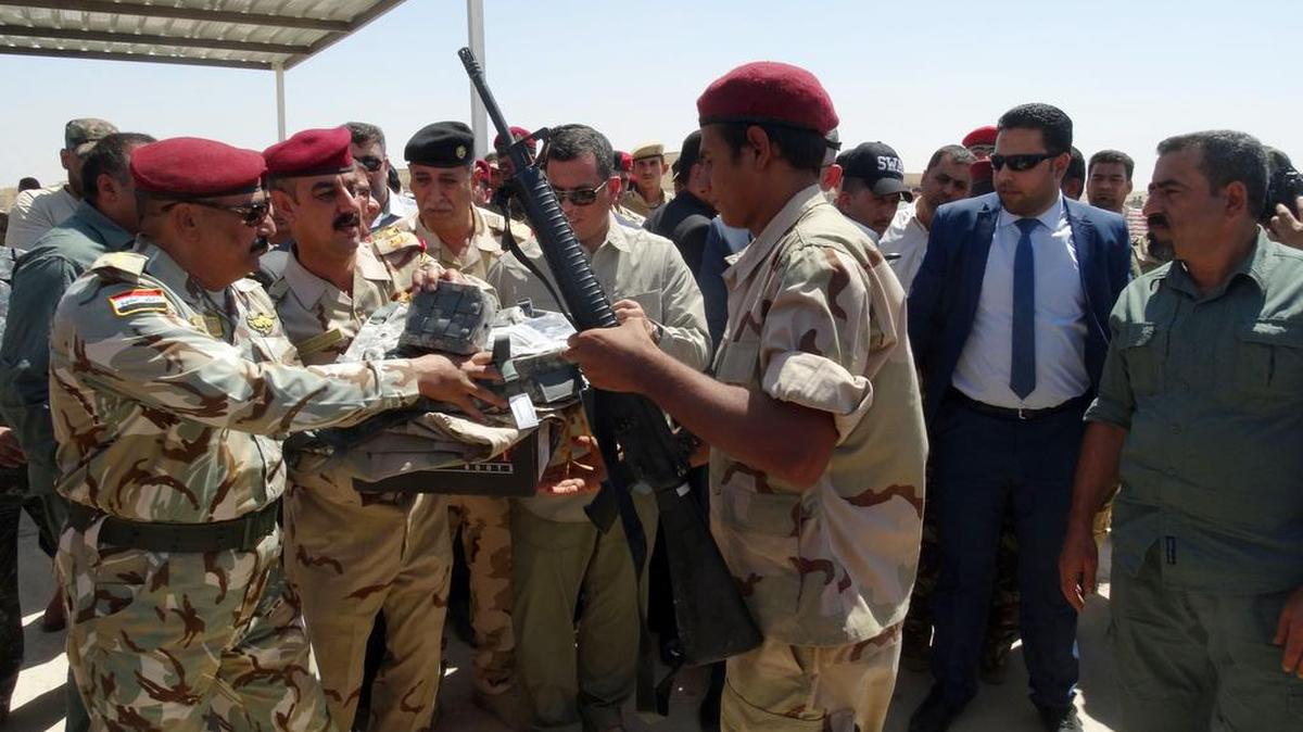 
A Sunni tribal volunteer at Habaniyah army base, center right, receives a new U.S.-made weapon to fight Islamic State militants to regain Ramadi, Iraq, on Thursday, Sept. 3, 2015.
