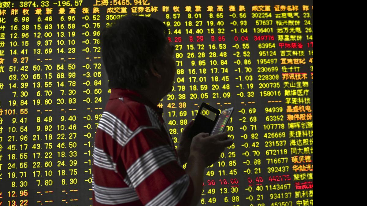
A man holds a smartphone, looking at an electric board displaying stock prices at a brokerage house in Hangzhou in east China's Zhejiang province Monday, July 27, 2015.
