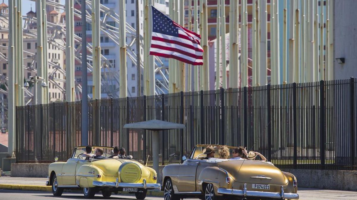 Tourists ride vintage American convertibles as they pass by the United States embassy in Havana, Cuba, Thursday, Feb. 18, 2016. President Barack Obama said that he will visit Cuba on March 21-22, making him the first sitting president in more than half a century to visit the island nation. (AP Photo/Desmond Boylan)