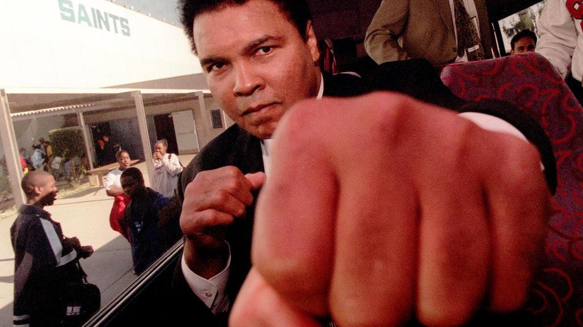 Muhammad Ali throws playful punch toward a photographer while visiting Locke High School in Los Angeles on December 4, 1996. Muhammad Ali died on Friday, June 3, 2016, at 74.
