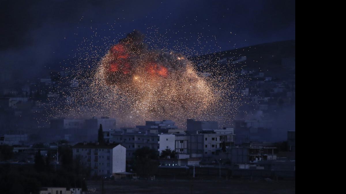 
In this Oct. 20, 2014, photo, thick smoke and flames from an airstrike by the U.S.-led coalition rise in Kobani, Syria. A report from a Syrian human rights group accuses the United States of killing dozens of civilians in airstrikes last week in northern Syria. The U.S. says civilians were not killed in the assault. 
