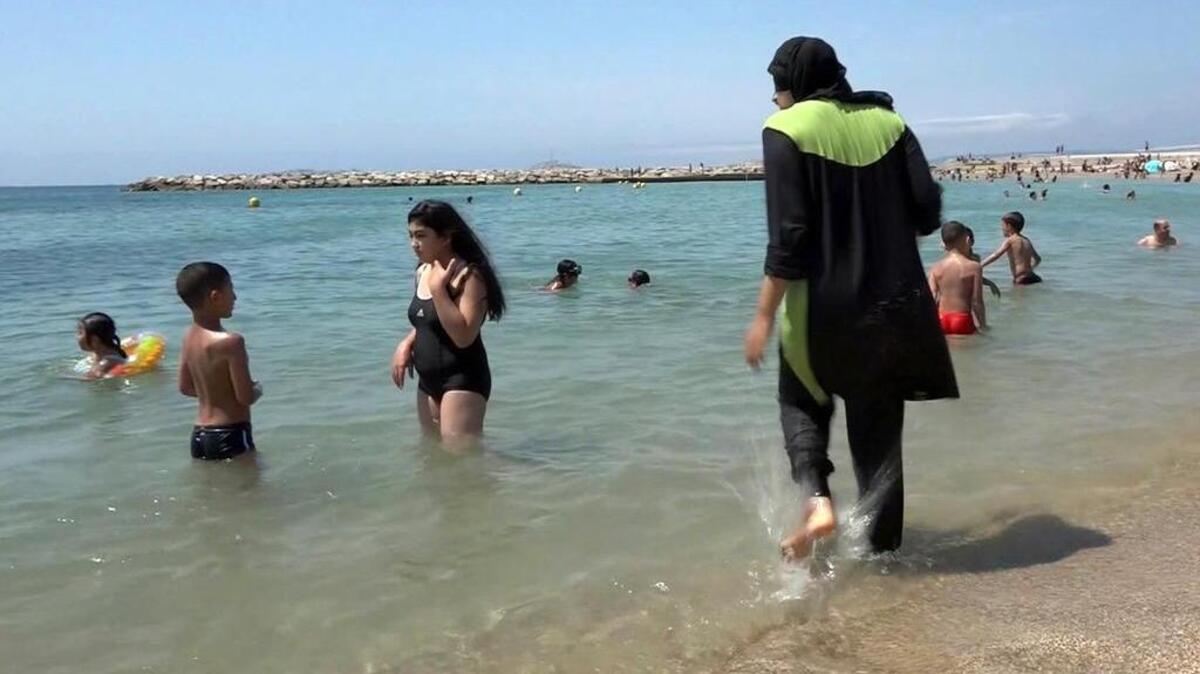 A Muslim woman wades into the sea wearing traditional Islamic dress earlier this month in Marseille, southern France. The French resort of Cannes has banned full-body, head-covering swimsuits worn by some Muslim women – sometimes called a burkini – from its beaches, citing security concerns.