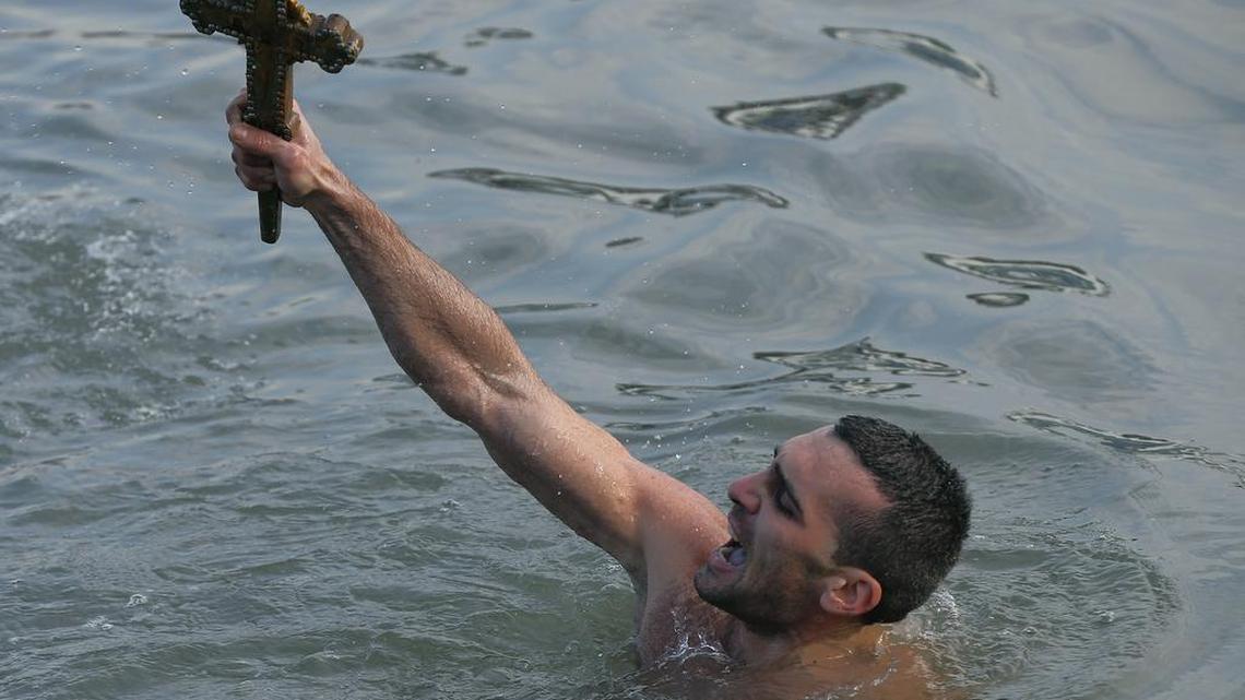 Nicolaos Solis, 28, from Greece, holds up the wooden cross that was thrown into the water at the Golden Horn in Istanbul on Wednesday by Ecumenical Patriarch Bartholomew I.