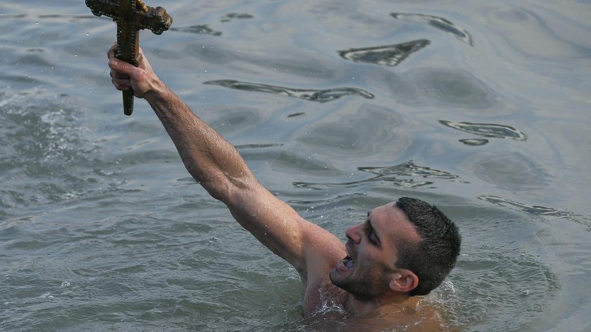 Nicolaos Solis, 28, from Greece, holds up the wooden cross that was thrown into the water at the Golden Horn in Istanbul on Wednesday by Ecumenical Patriarch Bartholomew I.
