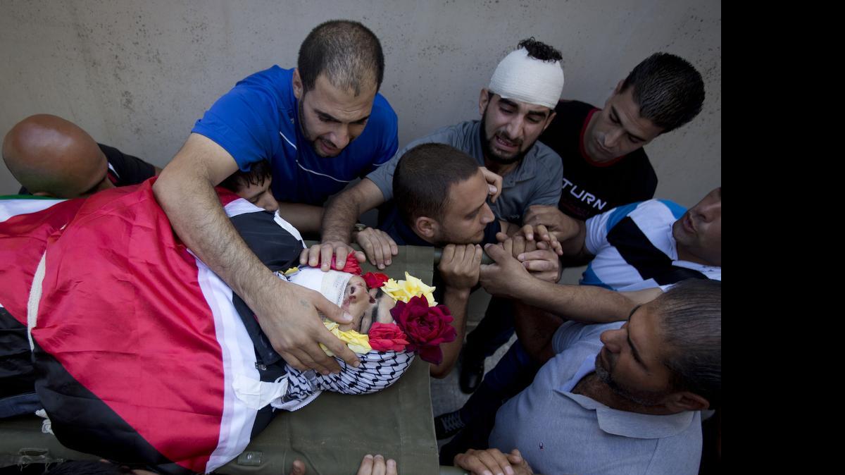 
Mourners surrounded the body of Mohammed Kasbah, 17, July 3 after he was killed by Israeli soldiers. On Monday, security camera video called in to question the official version of how Kasbah was killed. The video showed he was running away when he was shot.
