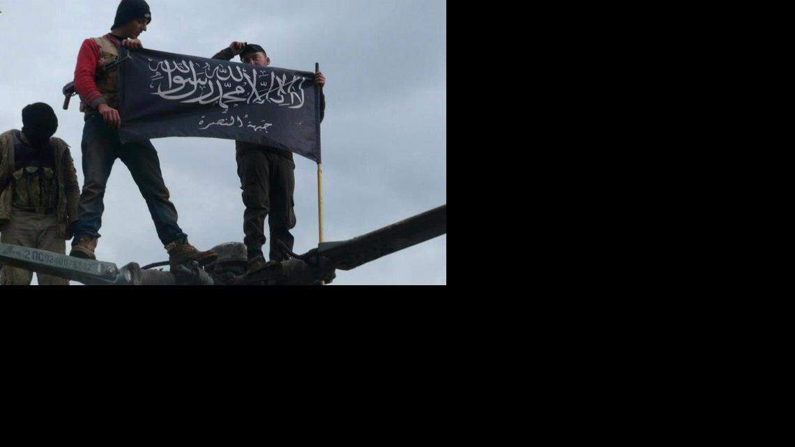 
 Rebels from al-Qaida-affiliated Jabhat al-Nusra, also known as the Nusra Front, wave their brigade flag on Jan. 11, 2013, as they step on the top of a Syrian air force helicopter at Taftanaz air base that was captured by the rebels in Idlib province, northern Syria. 
