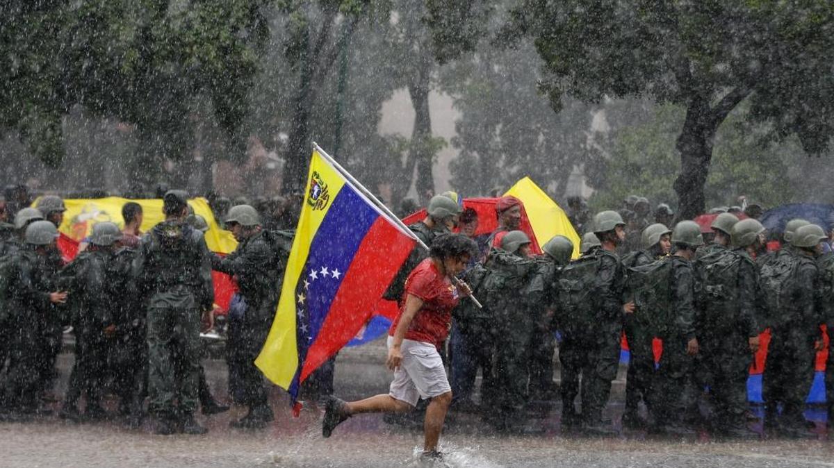 A follower of President Nicolas Maduro runs past a line of soldiers in Caracas, Venezuela, Saturday, Aug. 26, 2017.