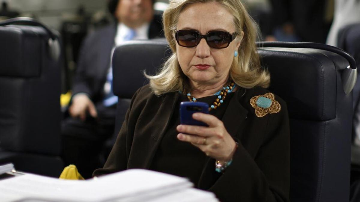 In this Oct. 18, 2011, file photo, then-Secretary of State Hillary Rodham Clinton checks her Blackberry from a desk inside a C-17 military plane upon her departure from Malta, in the Mediterranean Sea, bound for Tripoli, Libya.