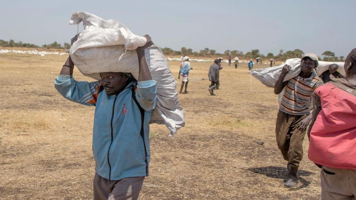 In this Monday, March 6, 2017 photo, South Sudanese men carry food distributed by the World Food Programme in Leer County Southern Leich State in South Sudan. An estimated 100,000 people are experiencing famine, and another 1 million people are on the brink of starvation, South Sudan's government and U.N. agencies said in late February. South Sudan is now Africa's largest migrant crisis as more than 3 million people have either fled the country or become internally displaced, according to the U.N.