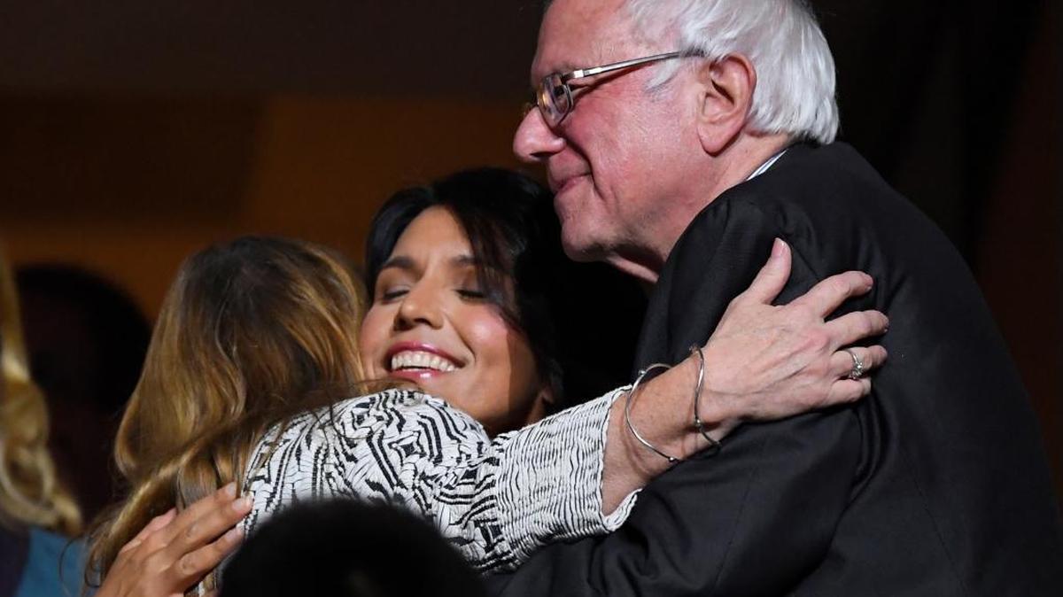 Former Democratic presidential candidate, Sen. Bernie Sanders, I-Vt., is embraced by wife, Jane, and Rep. Tulsi Gabbard, D-Hawaii, on Tuesday at the Democratic National Convention in Philadelphia.