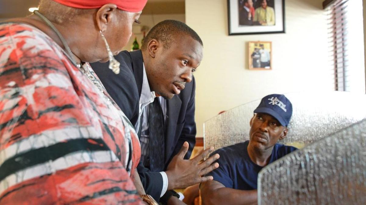 Akua Scott and Aaron McKinney, left and center, community organizers in South Florida, speak with customers at Jackson's Soul Food restaurant, a popular gathering place for many living in District 24, about voter turnout, in Overtown, Fla., on Oct. 9, 2014.