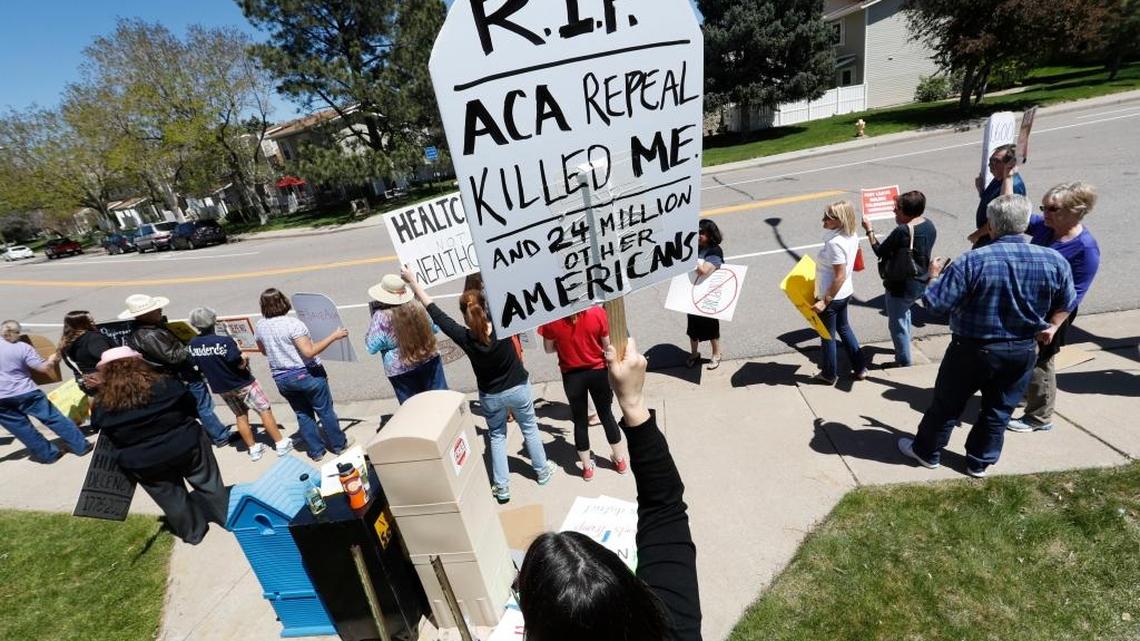 Lisa Moore of Denver holds up a sign during a protest outside the office of U.S. Rep. Mike Coffman, R-Colo., over the health care overhaul bill up for a vote in the U.S. House on Thursday, May 4, 2017, in Aurora, Colo. Advocacy groups will now turn their attention to Sen. Cory Gardner of Colorado, among others.