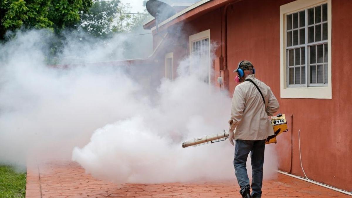 A Miami-Dade County mosquito control worker sprays around a home in the Wynwood area of Miami on Aug. 1, 2016.