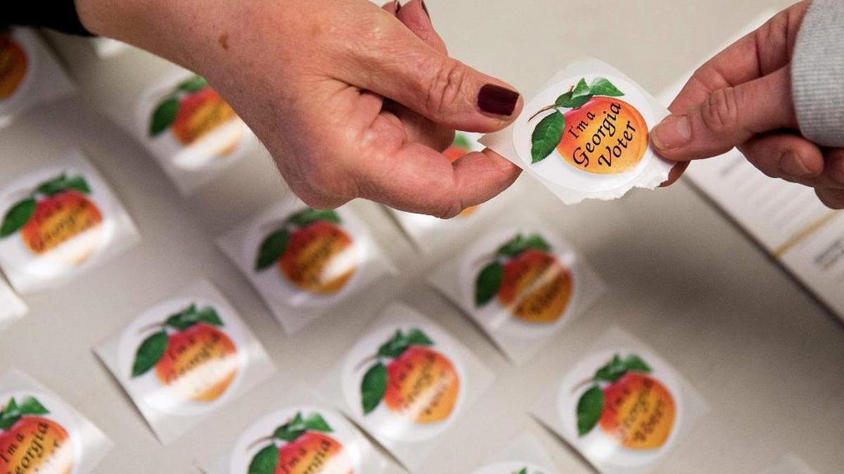Poll worker Delores Peterson, left, hands a sticker to a voter after they cast their ballot in Georgia's primary election at a polling site in Atlanta on March 1, 2016.