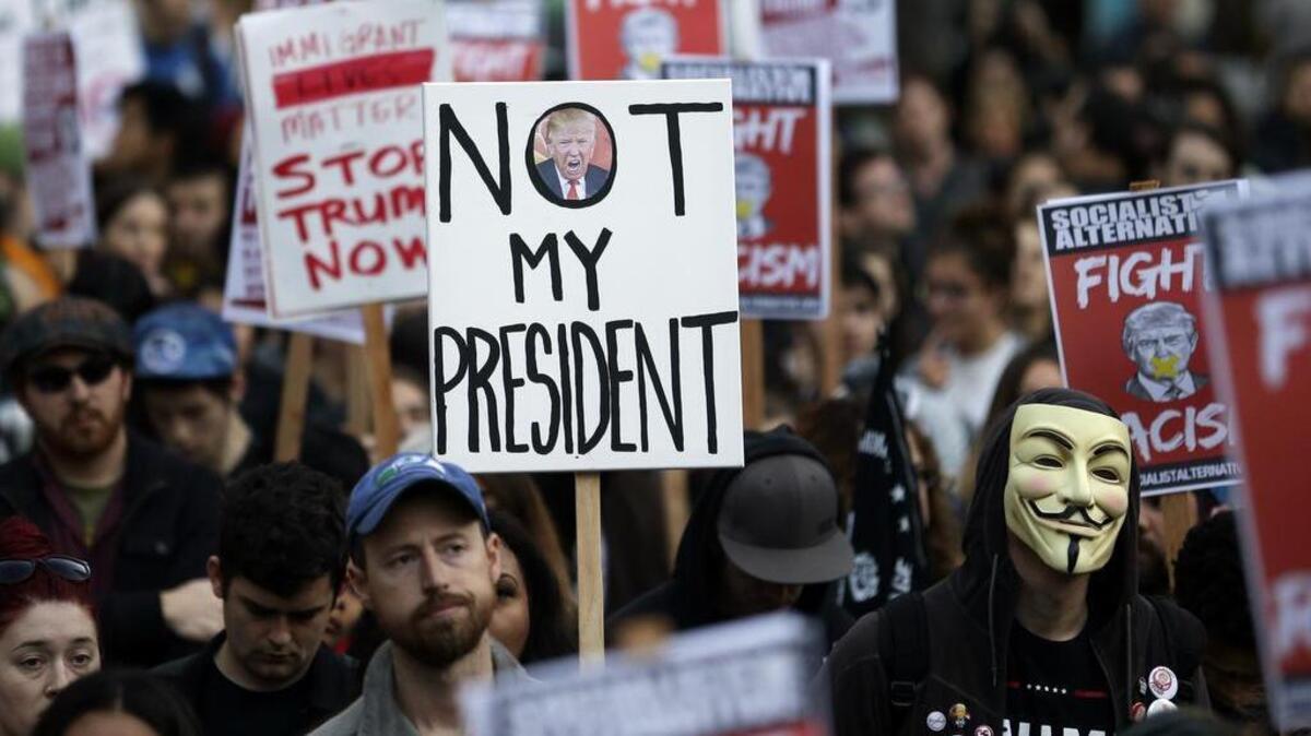 Protesters hold signs during a protest against the election of President-elect Donald Trump, Wednesday, Nov. 9, 2016, in downtown Seattle.