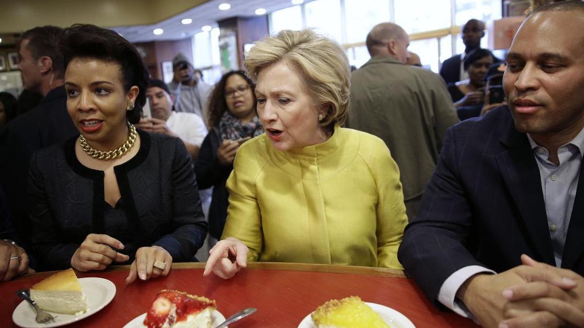 Democratic presidential candidate Hillary Clinton, center, talks with Rep. Hakeem Jeffries, D-N.Y., right, and Council Member Laurie Cumbo as she looks over the cheesecake offerings at Junior's restaurant in the Brooklyn borough of New York, April 9, 2016.