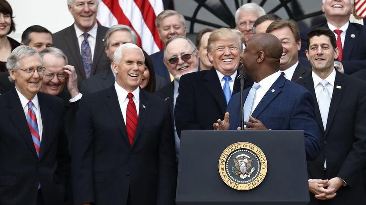 President Donald Trump smiles as Sen. Tim Scott, R-S.C., speaks during a bill passage event on the South Lawn of the White House in Washington, Wednesday, Dec. 20, 2017, to acknowledge the final passage of tax overhaul legislation by Congress.