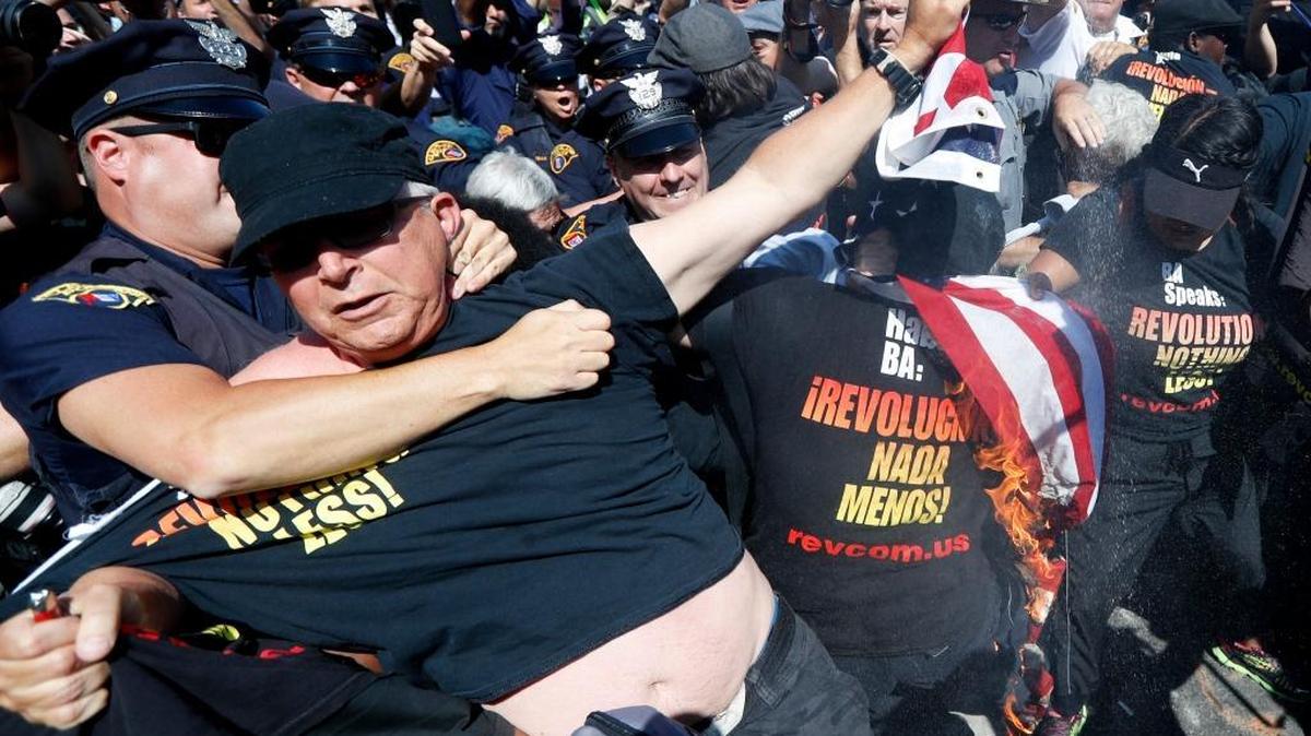 In this July 20, 2016, file photo, a law enforcement officer takes Gregory "Joey" Johnson into custody after he started to burn an American flag in Cleveland, during the third day of the Republican convention. President-elect Donald Trump said Tuesday that anyone who burns an American flag should face unspecified "consequences," such as jail or a loss of citizenship _ a move that was ruled out by the Supreme Court nearly three decades ago.