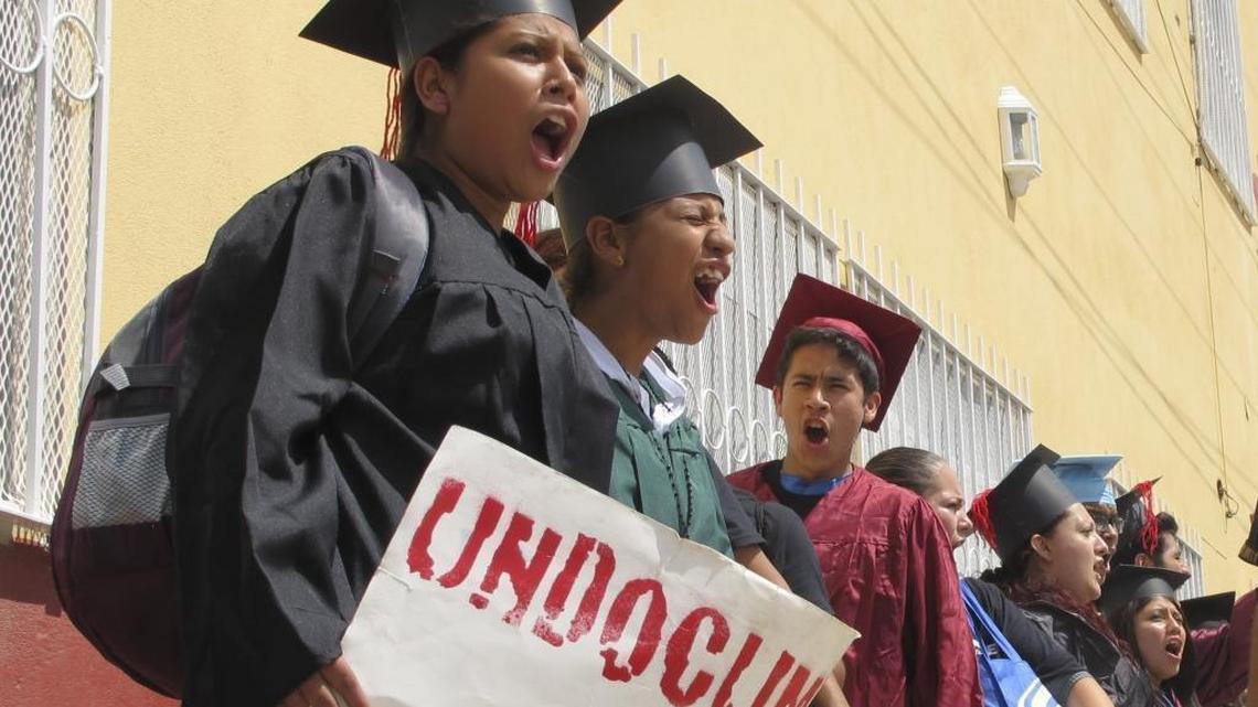 Wearing graduation-style caps and gowns, Mexican youth raised in the U.S, chant slogans outside a migrant shelter before crossing the international bridge from Nuevo Laredo, Mexico on Sept. 20, 2013. (AP Photo/Christopher Sherman, File)