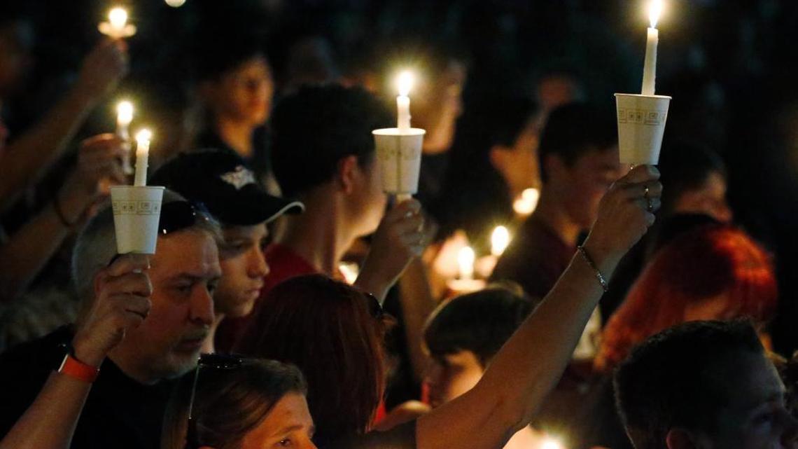 Attendees raise their candles at a candlelight vigil for the victims of the shooting at Marjory Stoneman Douglas High School, Thursday, Feb. 15, 2018, in Parkland, Fla. An orphaned 19-year-old with a troubled past and his own AR-15 rifle was charged with 17 counts of premeditated murder Thursday morning after being questioned for hours by state and federal authorities following the deadliest school shooting in the U.S. in five years.