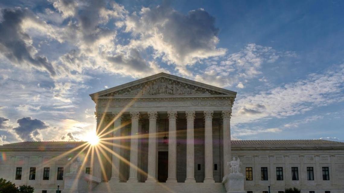 The sun flares in the camera lens as it rises behind the U.S. Supreme Court building in Washington on Sunday. The court announced their decision Monday on whether the Trump administration can enforce its travel ban.