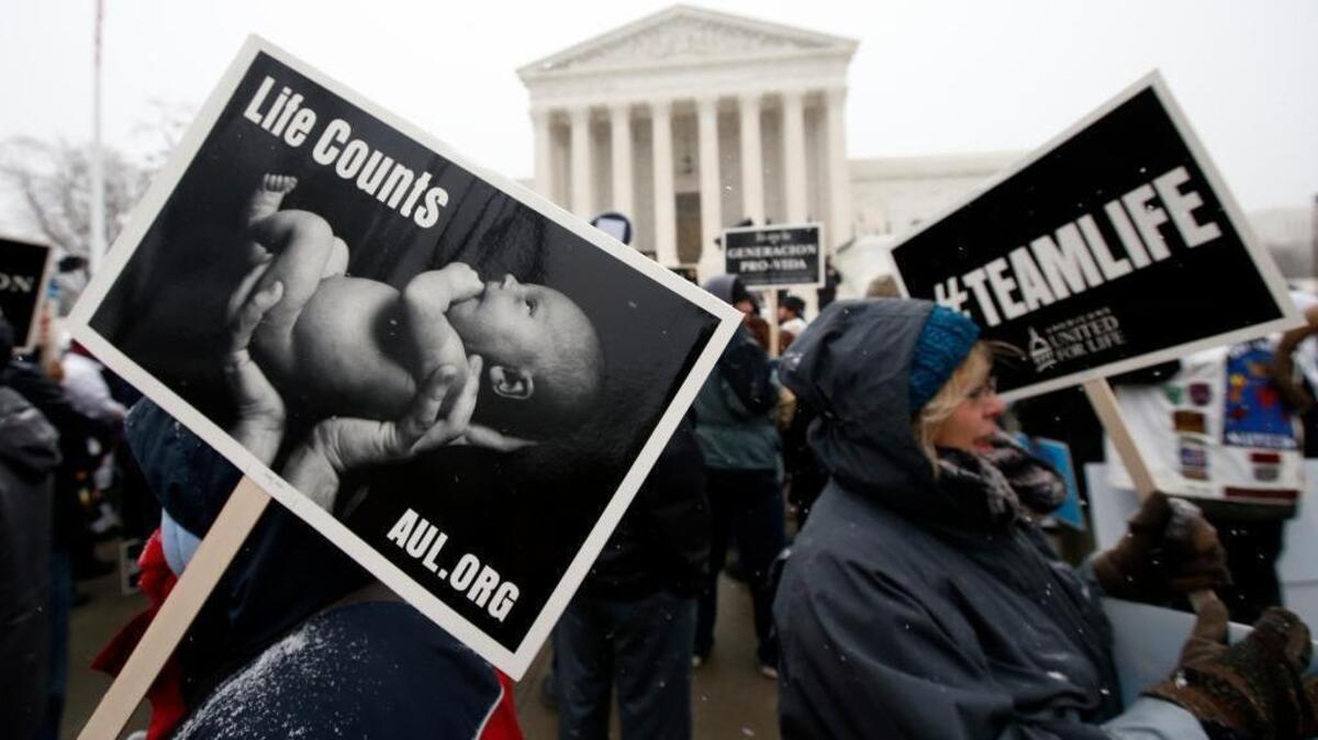 FILE – At the 2016 March for Life, attendees carry signs in front of the U.S. Supreme Court. The Jan. 22, 2016, annual rally was in Washington – an anniversary of the 1973 Roe v. Wade U.S. Supreme Court decision legalizing abortion.
