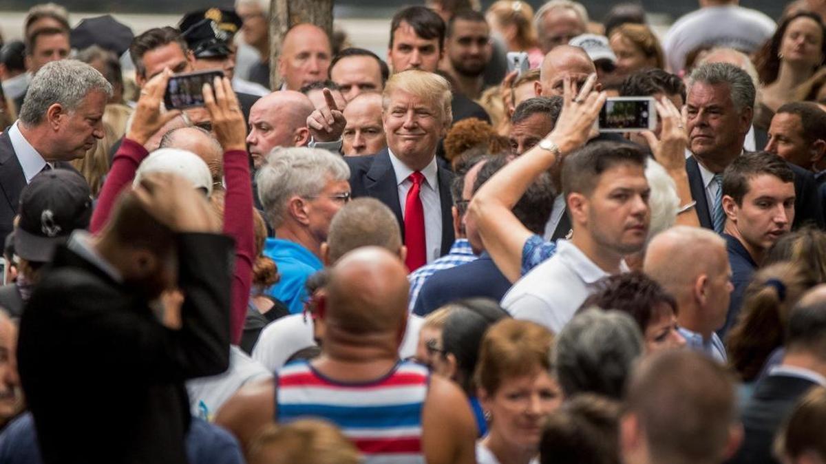 Republican presidential candidate Donald Trump, center, greets members of the audience as he attends a ceremony at the National September 11 Memorial, in New York, on Sept. 11, 2016.