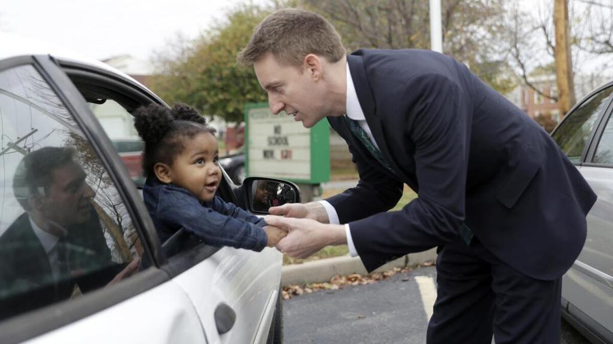 Missouri Democratic Senate candidate Jason Kander shakes hands Teh'Riyah Hinkle, 1, as she waits in a car with her aunt while another relative votes, Nov. 8, 2016, in St. Louis.