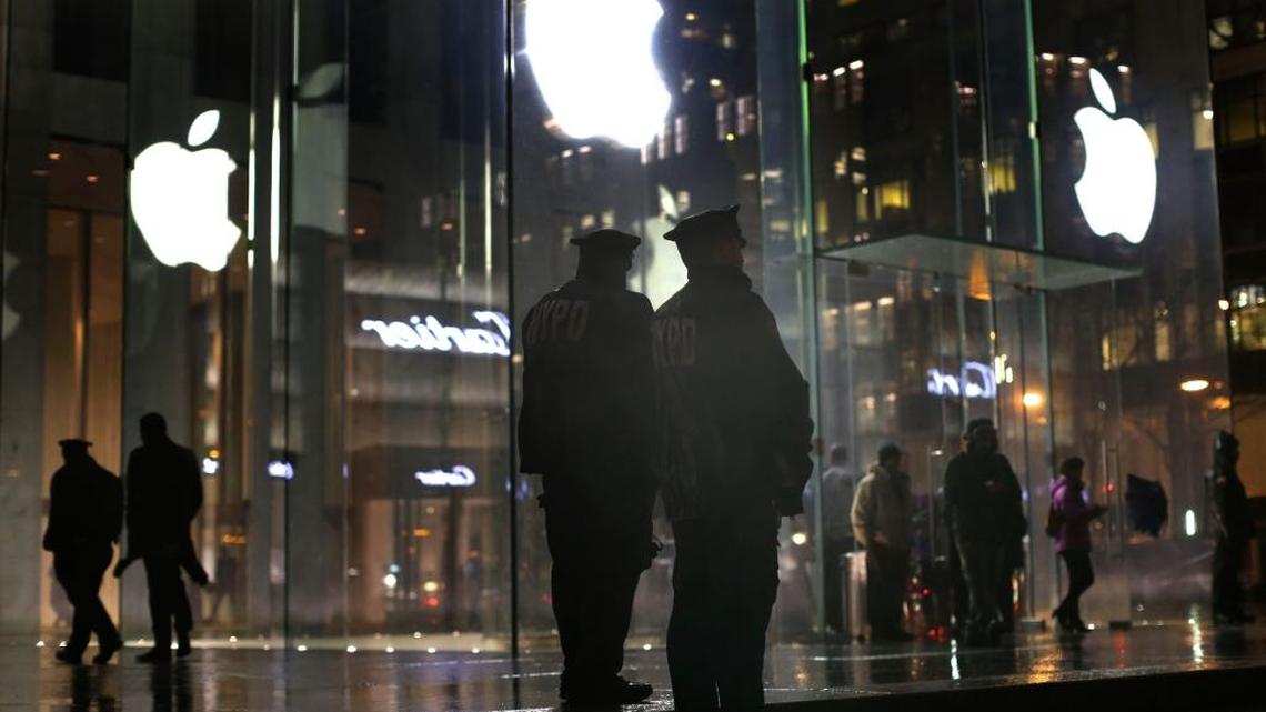 FILE – New York police officers stand outside an Apple Store during protests in February. Demonstrations were held to protest the FBI demanding that Apple help the government unlock an encrypted iPhone used by a gunman in December's mass murders in California.