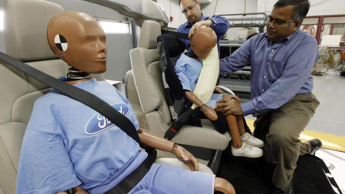 Edward DeSmet, left, and Srini Sundararajan adjust a crash dummy with an inflatable seat belt on a demonstrator at Ford Motor Co. in Dearborn, Mich., on Monday, Nov. 2, 2009.