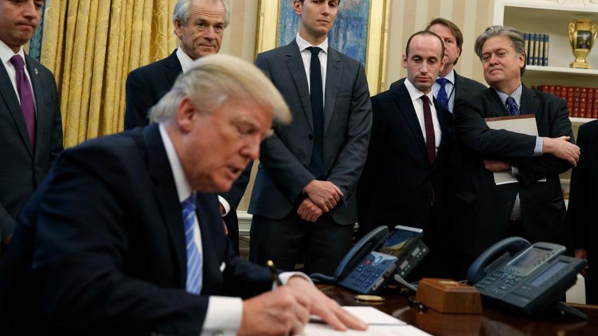 From left, White House Chief of Staff Reince Priebus, National Trade Council adviser Peter Navarro, senior adviser Jared Kushner, policy adviser Stephen Miller and chief strategist Steve Bannon watch as President Donald Trump signs an executive order in the Oval Office of the White House, Jan. 23, 2017, in Washington.