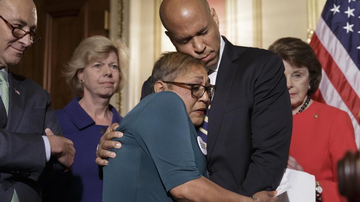 The Rev. Sharon Risher, a clinical trauma chaplain in Dallas, who lost her mother, Ethel Lance, and two cousins in the racially motivated shooting last year at historic Emanuel AME Church in Charleston, S.C., is embraced by Sen. Cory Booker, D-N.J., during a news conference by Democratic senators calling for gun control legislation. From left are Sens. Charles Schumer, D-N.Y., Tammy Baldwin, D-Wis., and Dianne Feinstein, D-Calif.