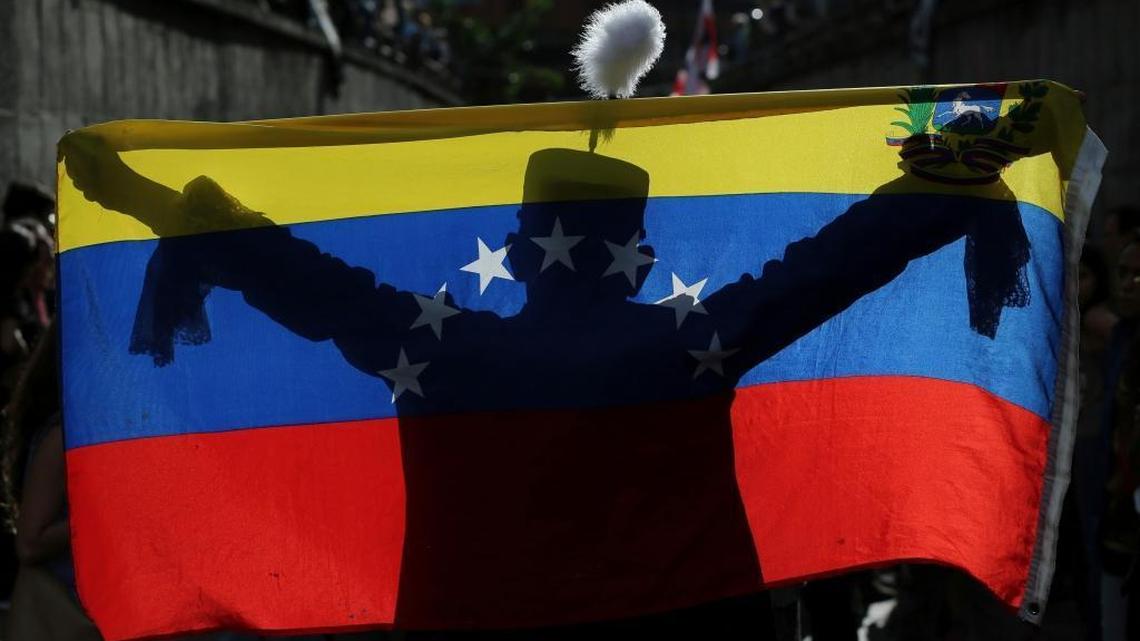 A demonstrator dressed as Venezuelan independence hero Simon Bolivar waves a national flag during a tribute to those killed during protests against Venezuela's President Nicolas Maduro, in Caracas, Venezuela, Monday, July 24, 2017. The opposition is staging daily protests days before President Maduro launches the rewriting of the country's constitution.
