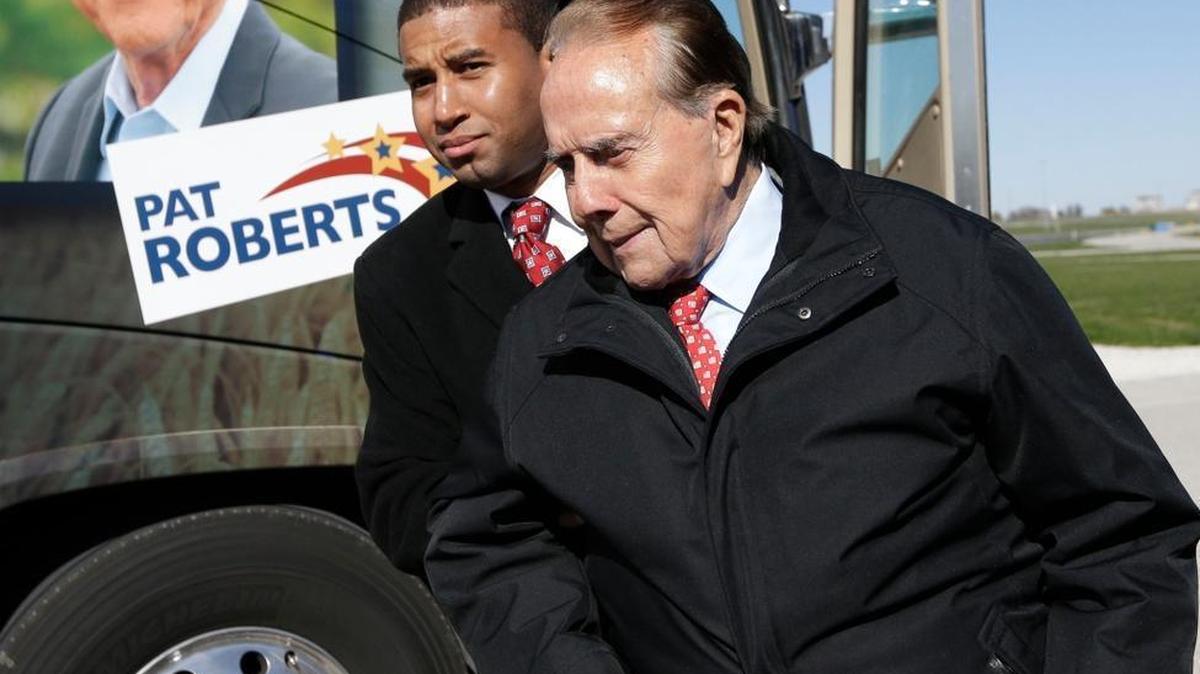 Former Sen. Bob Dole, R-Kan., is helped to his position during a campaign stop in support of Sen. Pat Roberts and Gov. Sam Brownback in Kansas City, Kan., on Friday, Oct. 31, 2014.