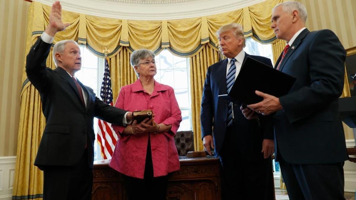President Donald Trump watches as Vice President Mike Pence administers the oath of office to Attorney General Jeff Sessions, accompanied by his wife Mary on Thursday in the Oval Office of the White House in Washington.