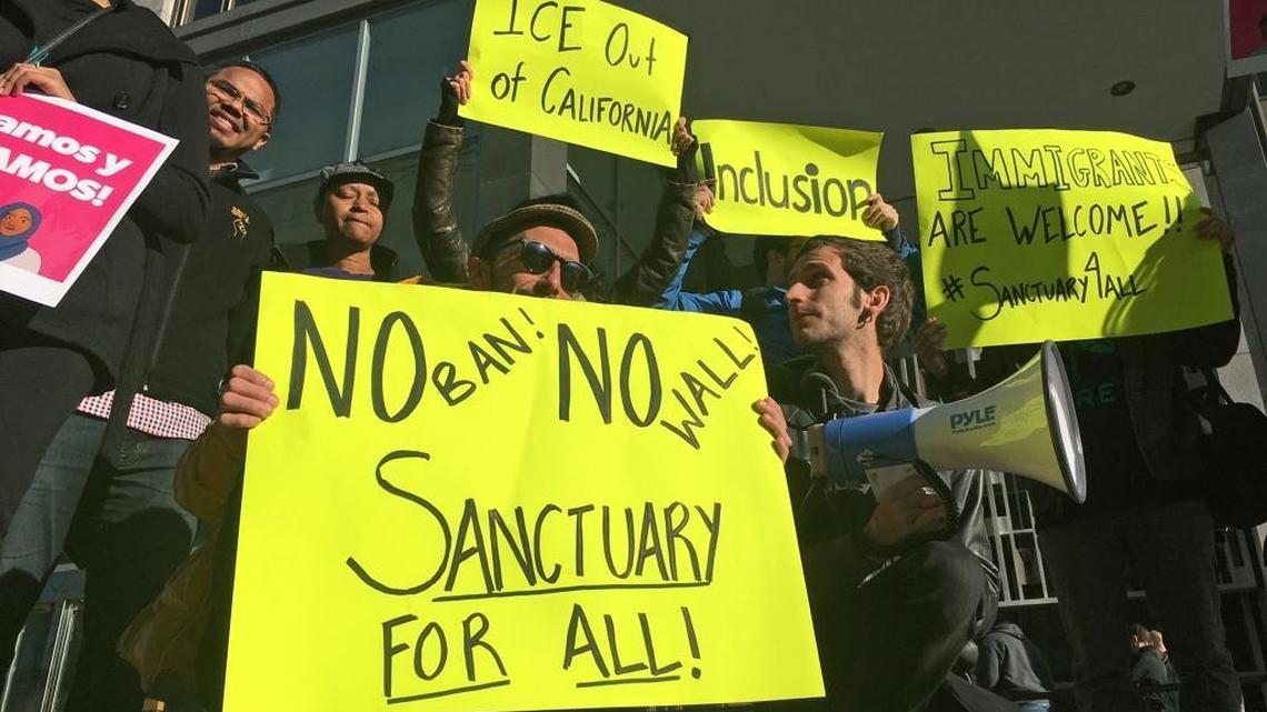 Protesters hold up signs outside a courthouse where a federal judge will hear arguments in the first lawsuit challenging President Donald Trump's executive order to withhold funding from communities that limit cooperation with immigration authorities Friday, April 14, 2017, in San Francisco.