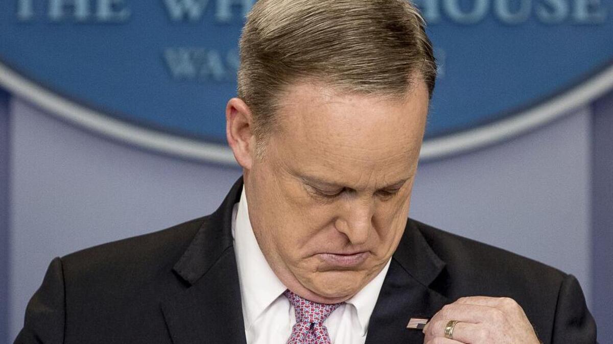 White House press secretary Sean Spicer adjusts his American flag pin after he was told that it was upside down, Friday, March 10, 2017, during the daily press briefing at the White House in Washington.