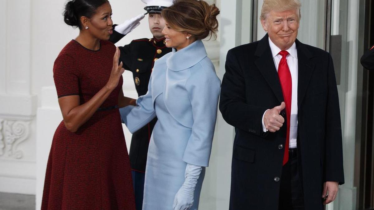 President-elect Donald Trump gives a thumbs-up as first lady Michelle Obama and Melania Trump talk at the White House in Washington, Friday, Jan. 20, 2017.