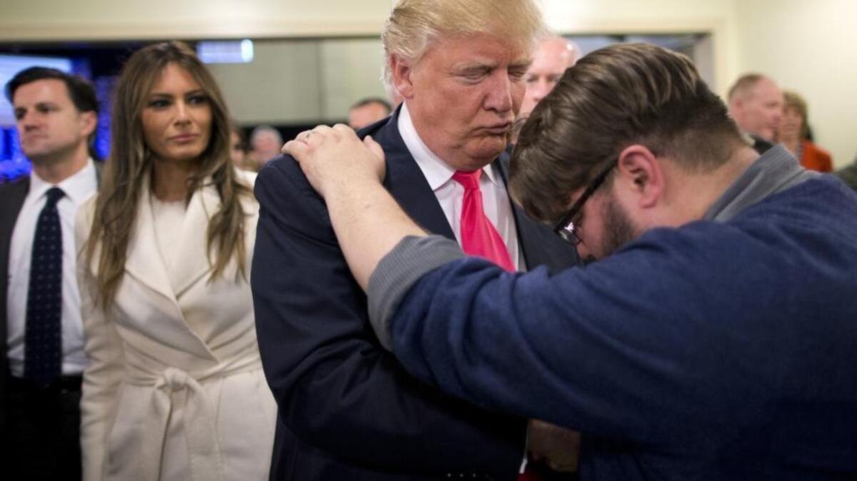 Pastor Joshua Nink, right, prays for Republican presidential candidate Donald Trump, as his wife, Melania, left, watches after a Sunday service at First Christian Church, in Council Bluffs, Iowa. Trump has vowed to “totally destroy” a 1950s law preventing churches from endorsing or opposing political candidates.