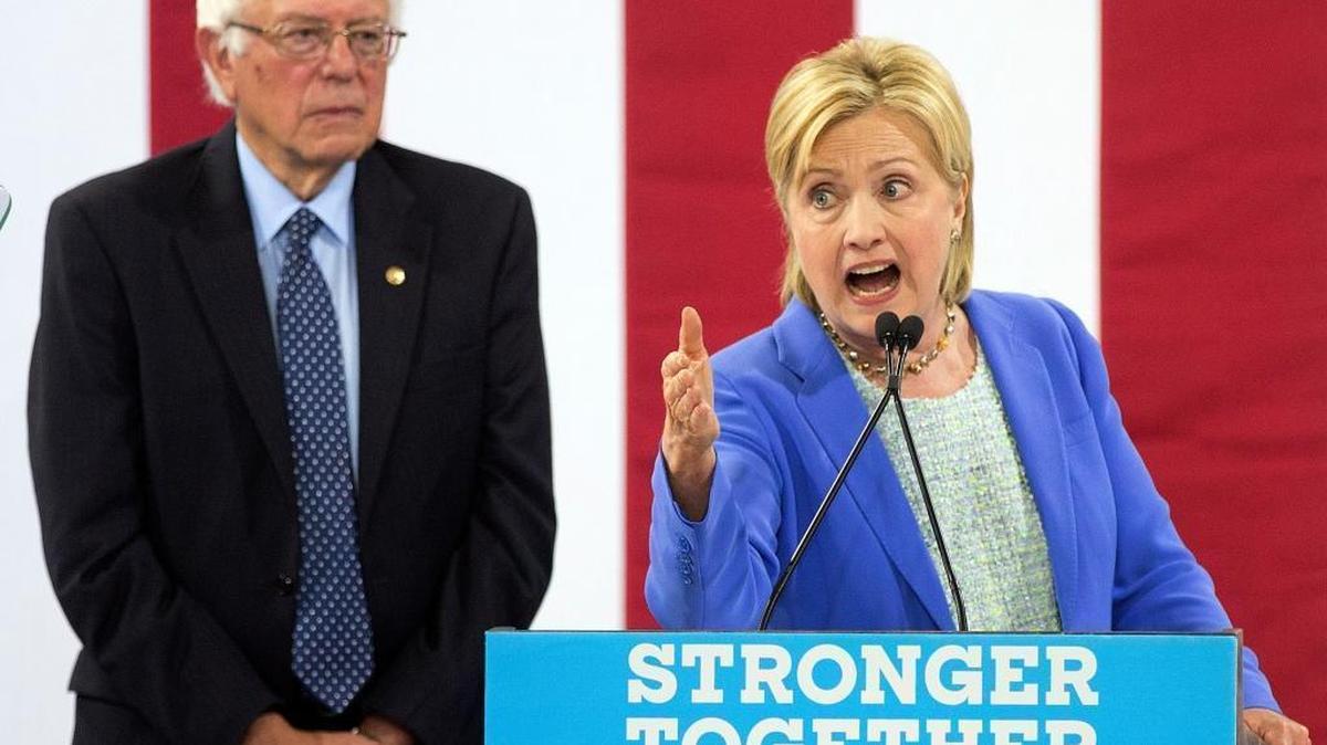 Sen. Bernie Sanders listens as Democratic presidential candidate Hillary Clinton speaks during a rally in Portsmouth, N.H., on July 12, 2016, where Sanders endorsed Clinton for president.